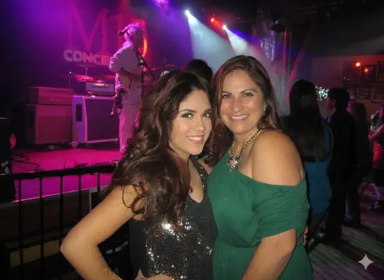 Debra Bollman with her daughter on stage during a concert, smiling and professional.
