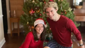 Amy Corenswet and David Corenswet posing together in a Christmas-themed setting, smiling in festive outfits